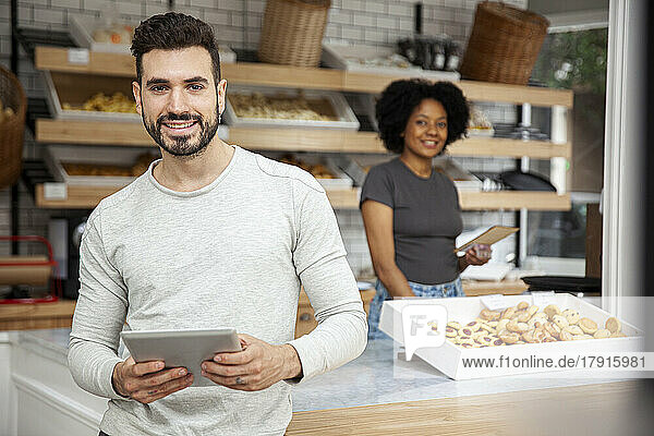 Bakery owner holding digital tablet while looking at the camera