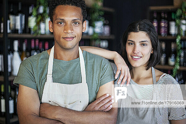 Wine store owner with arms crossed standing next to business partner