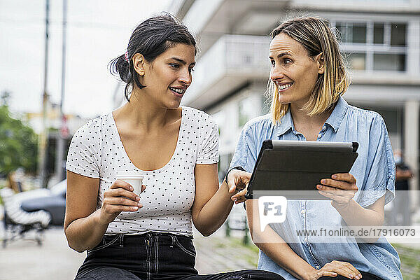 Front view mid-shot of two female co-workers talking about work matters while working outdoors