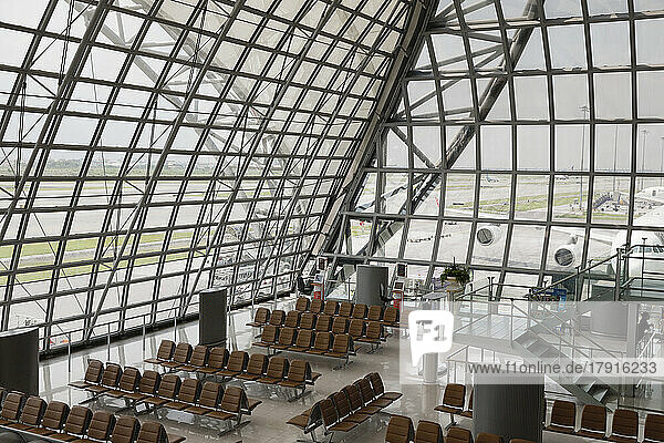 Flugsteig und Sitze am Flughafen Bangkok mit Blick auf die Flugzeuge durch die Glasfenster und -wände.