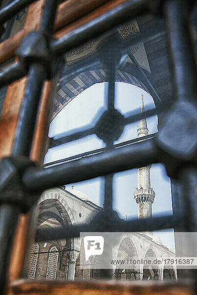 Die Stadt Istanbul  ein Wahrzeichen  ein hohes Minarett und Bögen mit Stein- und Laubsägearbeiten und Blick durch Metalltore oder Gitter.