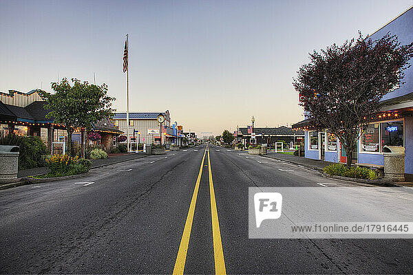 Road on main street running through empty town at dawn.