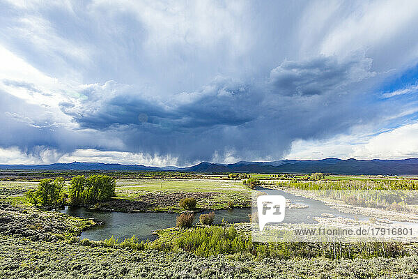 Usa  Idaho  Bellevue  Storm clouds above green field with creek