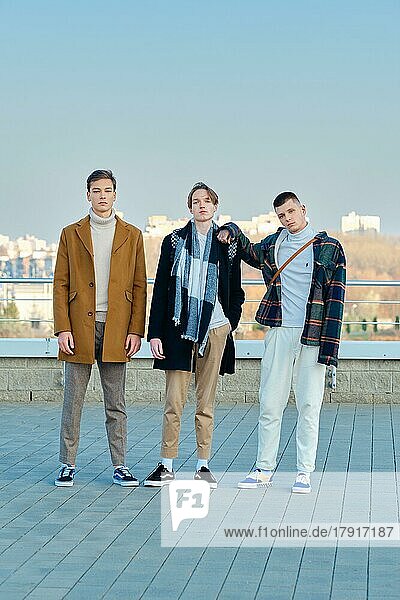 Drei junge Männer in Herbstkleidung gehen die Straße entlang