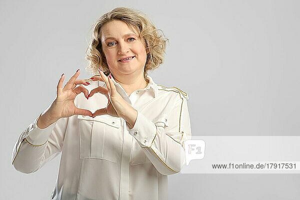 Glückliche ältere Frau zeigt Liebe Geste. Frau mittleren Alters faltete Handflächen in der Form eines Herzens