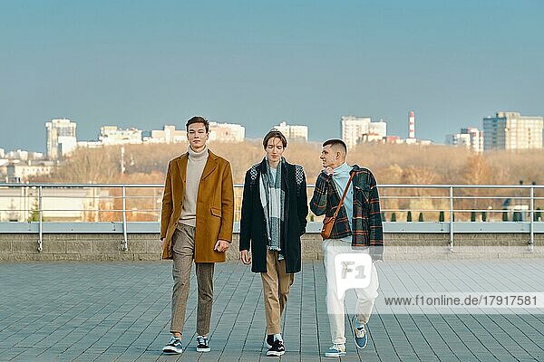 Drei junge Männer in Herbstkleidung gehen die Straße entlang