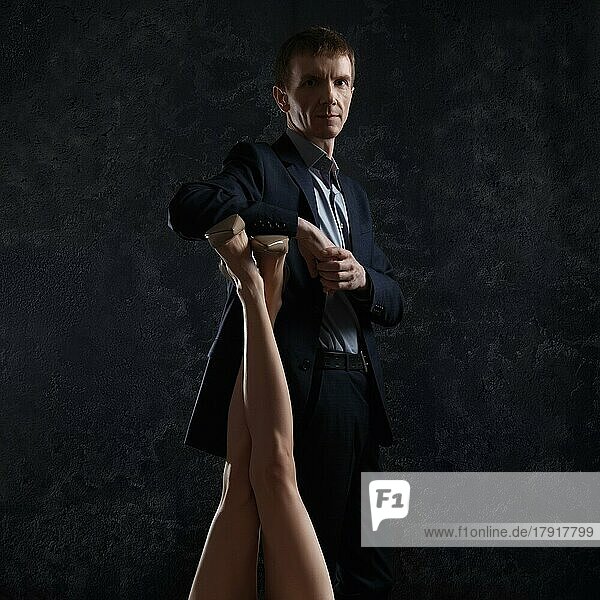 Man in business suit leans on female legs raised up