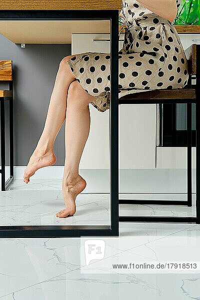 Seitenansicht von barfuß weiblichen Beinen unter dem Tisch zu Hause