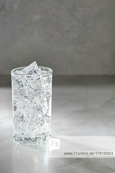 Glas mit Mineralwasser mit Eis auf Marmor Hintergrund