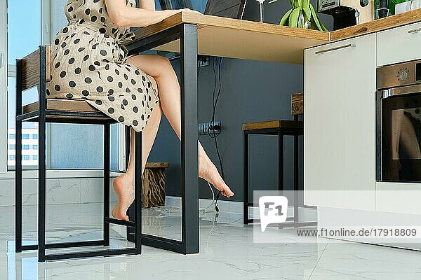 Seitenansicht von barfuß weiblichen Beinen unter dem Tisch zu Hause