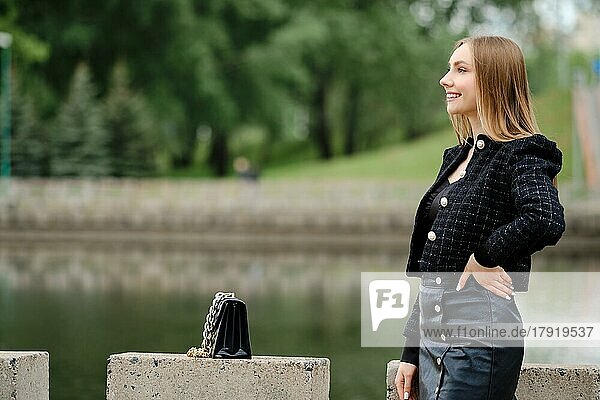 Junge fröhliche Frau posiert im Freien mit einem Fluss im Hintergrund