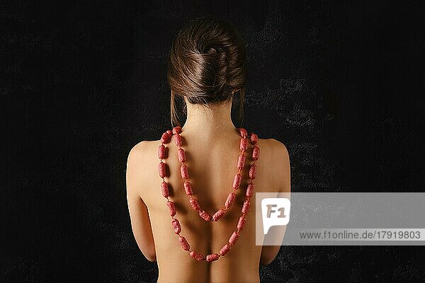 Junge Frau trägt kleine Piccolini-Würstchen mit Gewürzen als Perlen