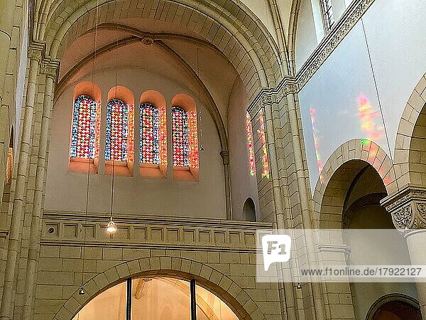 Sun shines through four stained glass windows above main portal of Benedictine Abbey Gerleve casts colourful light into nave  Gerleve  Münsterland  North Rhine-Westphalia  Germany  Europe