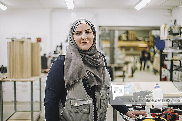 Porträt einer lächelnden Schreinerin mit Kopftuch in einer Werkstatt