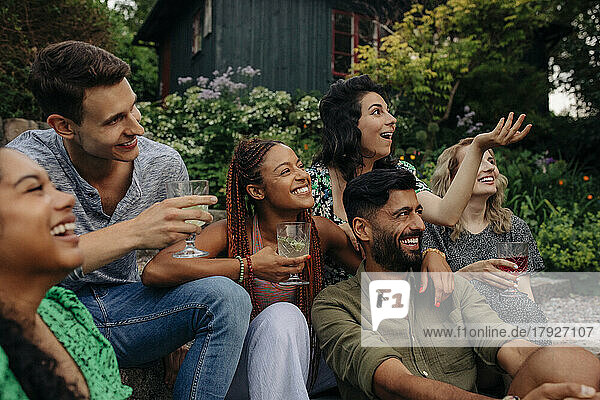 Glückliche männliche und weibliche Freunde mit Getränken  die sich auf einer Gartenparty amüsieren