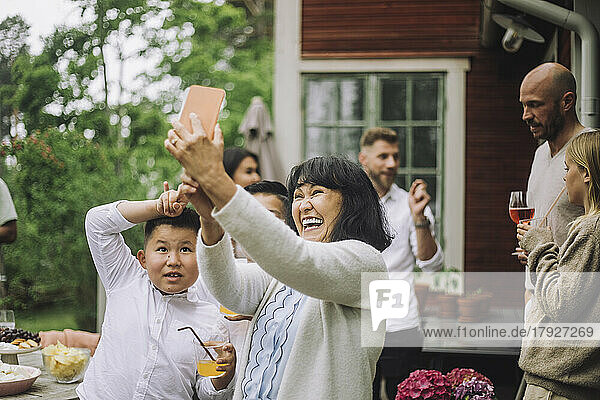 Glückliche Großmutter nimmt Selfie durch Smartphone mit Enkelkindern auf Party
