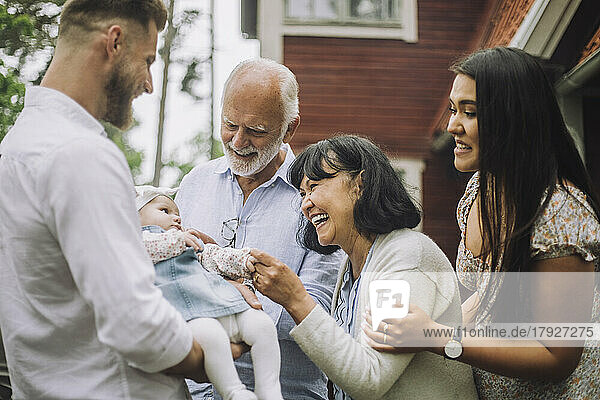 Happy multiracial family playing with baby girl at dinner party