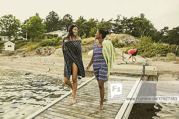 Mutter und Tochter kommunizieren miteinander  während sie im Urlaub auf dem Bootssteg spazieren gehen