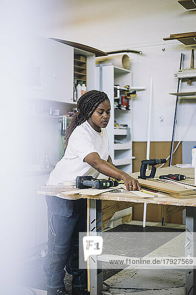 Female carpenter measuring while standing at workbench