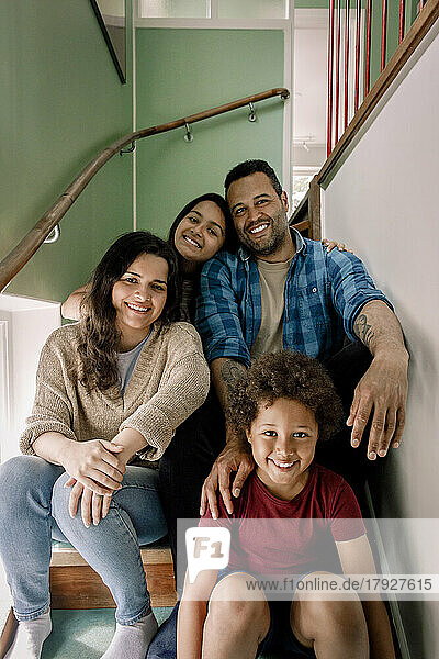 Porträt einer glücklichen Familie  die zusammen auf einer Treppe zu Hause sitzt