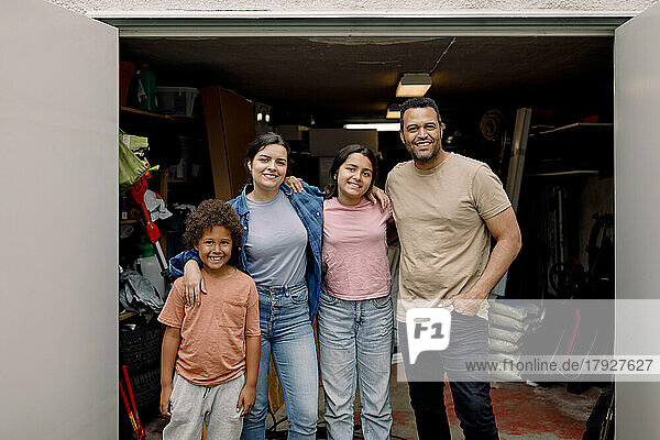 Porträt einer glücklichen gemischtrassigen Familie  die sich vor einem Lagerraum in den Armen liegt