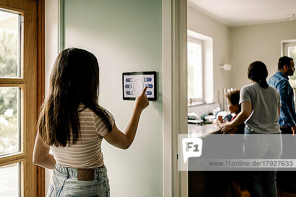 Girl using smart home app on digital tablet while standing near doorway