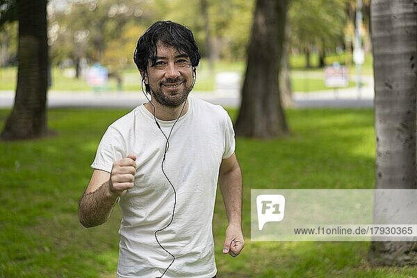 Portrait of handsome attractive mature bearded athletic latin man guy 40s in casual white t-shirt running at a park