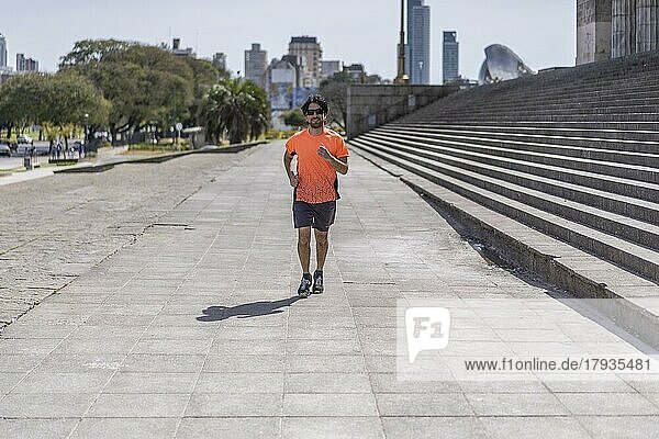 Porträt von gut aussehend attraktiv reifen bärtigen sportlichen lateinischen Mann Kerl 40s in orange T-Shirt läuft auf der Straße