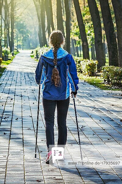 Nordic-Walking-Abenteuer und Trainingskonzept  Frau wandert mit Nordic-Walking-Stöcken im Park