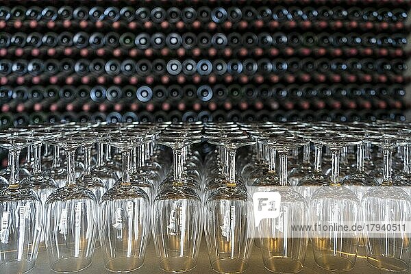 Leere Weingläser mit vielen gestapelten Flaschen im Hintergrund  Vorbereitung auf eine Weinverkostung in einem Weingut auf Lanzarote  Spanien  Europa