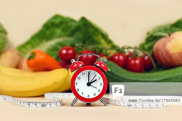 Konzept zum Abnehmen  indem man sich nur zu bestimmten Zeiten gesund ernährt  mit Gemüse  Obst  Maßband und Uhr