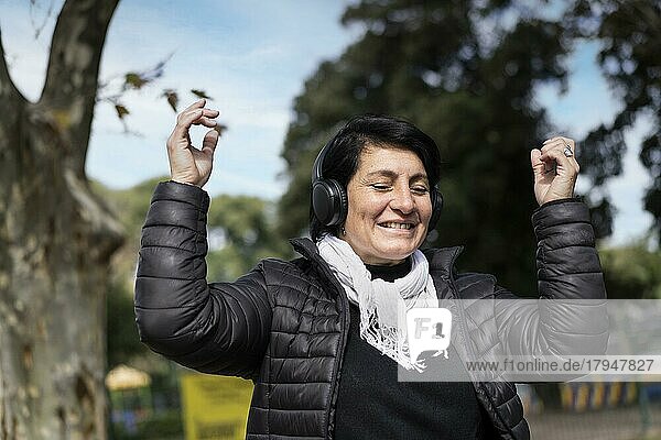 Lateinamerikanische Frau  die im Freien mit Kopfhörern Musik hört. Ausdruck von Glück  gewinnende Haltung. Textfreiraum