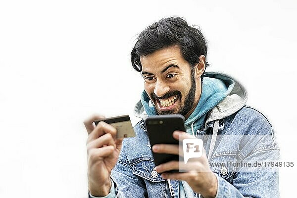 Lateinamerikanischer Mann  der eine Kreditkarte benutzt  um eine Online-Zahlung auf seinem Smartphone vorzunehmen. gemischtrassiger Mann  der sein Mobiltelefon zum Online-Shopping benutzt. Ein Mann benutzt ein Smartphone  um Kreditkartentransaktionen über eine App zu überprüfen. Weißer Hintergrund