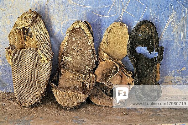 Marode  zerfallene Schuhe lehnen an blauer Wand  verrottete Schuhe am Boden  verrotteter Schuh  Schuhwrack  vergammelter Treter  ausgelatschter Schuh  abgetragener Schuh