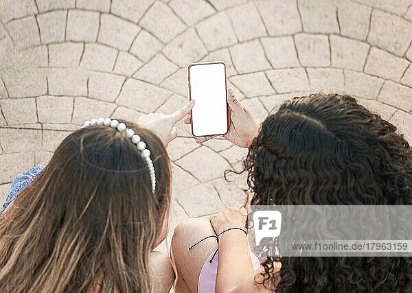 Freundin zeigt ihren Handy-Bildschirm  zwei Mädchen zeigen auf ihr Handy  Mädchen zeigt ihr Smartphone ihrer Freundin
