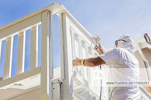 Maler mit Gesichtsschutz bei der Lackierung einer Terrasse eines Hauses