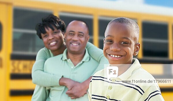 Stolze afroamerikanische Eltern und kleiner Junge in der Nähe des Schulbusses