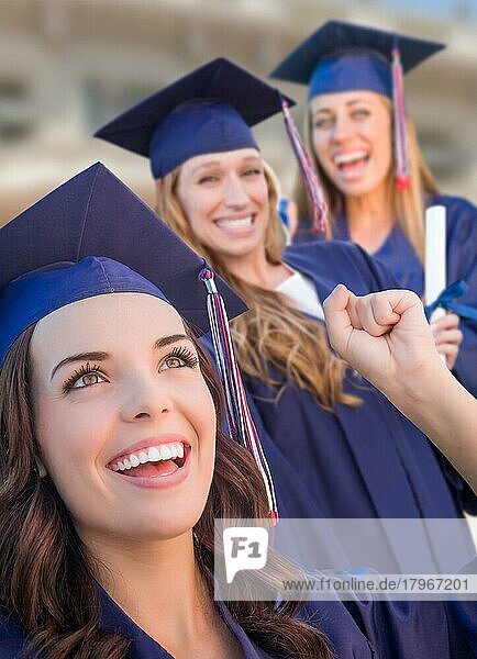 Happy graduating group of girls in cap and gown celebrating on campus