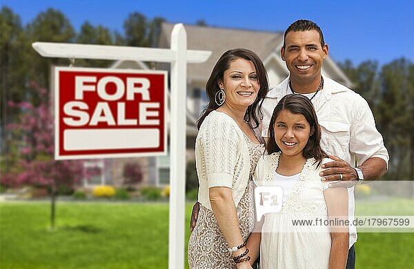 Hispanische Mutter  Vater und Tochter vor ihrem neuen Haus mit dem Schild Haus zu verkaufen
