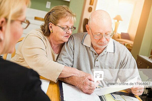 Älteres erwachsenes Paar  das mit einem Agenten bei der Unterzeichnung Dokumente in ihrer Wohnung durchgeht