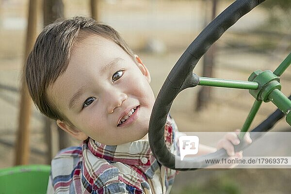 Entzückender gemischtrassiger Junge  der auf dem Traktor im Kürbisfeld spielt
