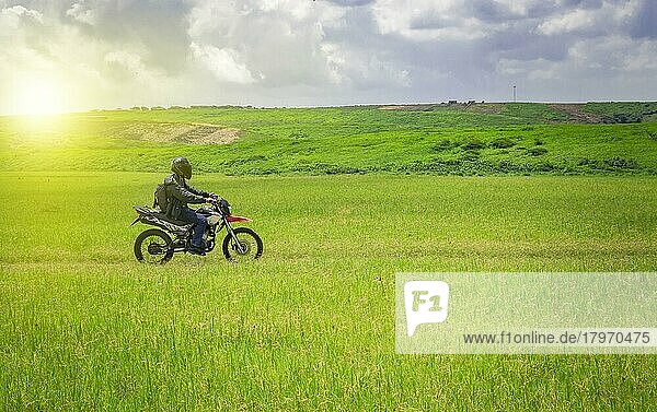 Biker Mann auf einer Landstraße  junger Mann auf seinem Motorrad unterwegs durch die Landschaft mit Kopie Raum  Mann fährt Motorrad auf dem Lande