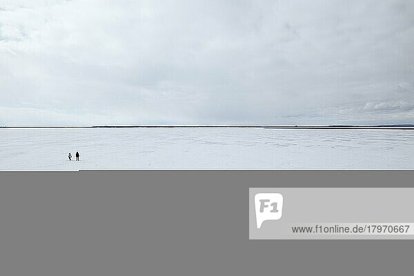 Zwei Menschen stehen auf einer weiten  zugefrorenen Flusslandschaft  Sankt-Lorenz-Strom  Provinz Quebec  Kanada  Nordamerika