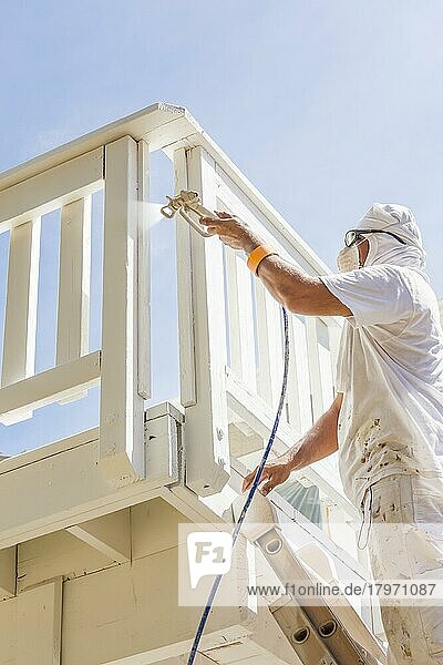 Maler mit Gesichtsschutz bei der Lackierung einer Terrasse eines Hauses