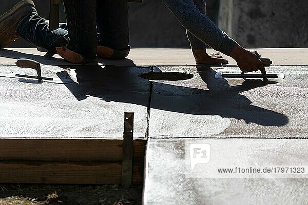 Bauarbeiter beim Glätten von nassem Zement mit Kellenwerkzeugen