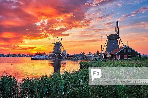 Ländliche Szene in den Niederlanden  Windmühlen am berühmten Touristenort Zaanse Schans in Holland bei Sonnenuntergang mit dramatischem Himmel  Zaandam  Niederlande  Europa