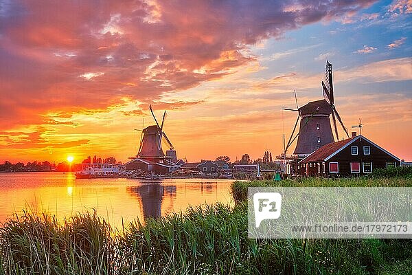 Ländliche Szene in den Niederlanden  - Windmühlen am berühmten Touristenort Zaanse Schans in Holland bei Sonnenuntergang mit dramatischem Himmel  Zaandam  Niederlande  Europa