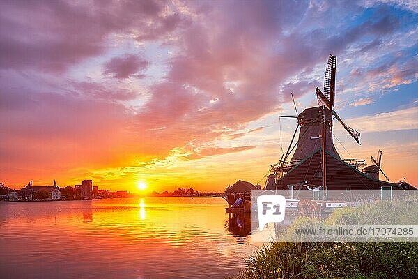 Ländliche Szene in den Niederlanden  - Windmühlen am berühmten Touristenort Zaanse Schans in Holland bei Sonnenuntergang mit dramatischem Himmel  Zaandam  Niederlande  Europa