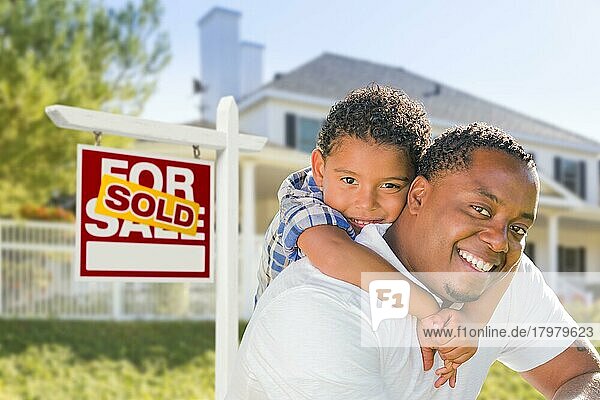 Afroamerikanischer Vater und gemischtrassiger Sohn vor einem verkauften Haus  das zum Verkauf steht  Immobilienschild und neues Haus