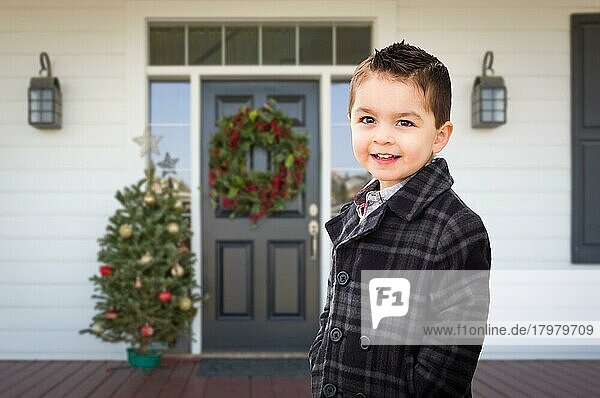 Junger gemischtrassiger Junge auf der Veranda eines Hauses mit Weihnachtsschmuck